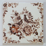 Vintage-style kitchen trivet on ceramic tile. Painting with 2 birds and flowers in brown colors. Retro-style kitchen decor.