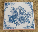 Vintage-style kitchen trivet on ceramic tile. Painting with 2 birds and flowers in blue colors. Retro-style kitchen decor in blue colors.